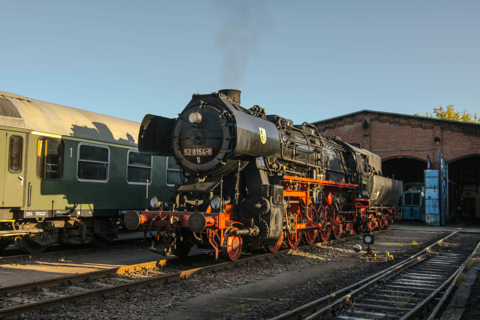 Sie sollten sehen: die Dampflokomotive 52 8154 steht vor dem Lokschuppen und raucht ein wenig vor sich hin.