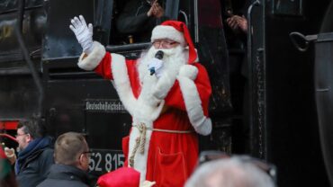 Das Bild zeigt den Weihnachtsmann beim Absteigen von der Dampflok des Leipziger Eisenbahnmuseums.