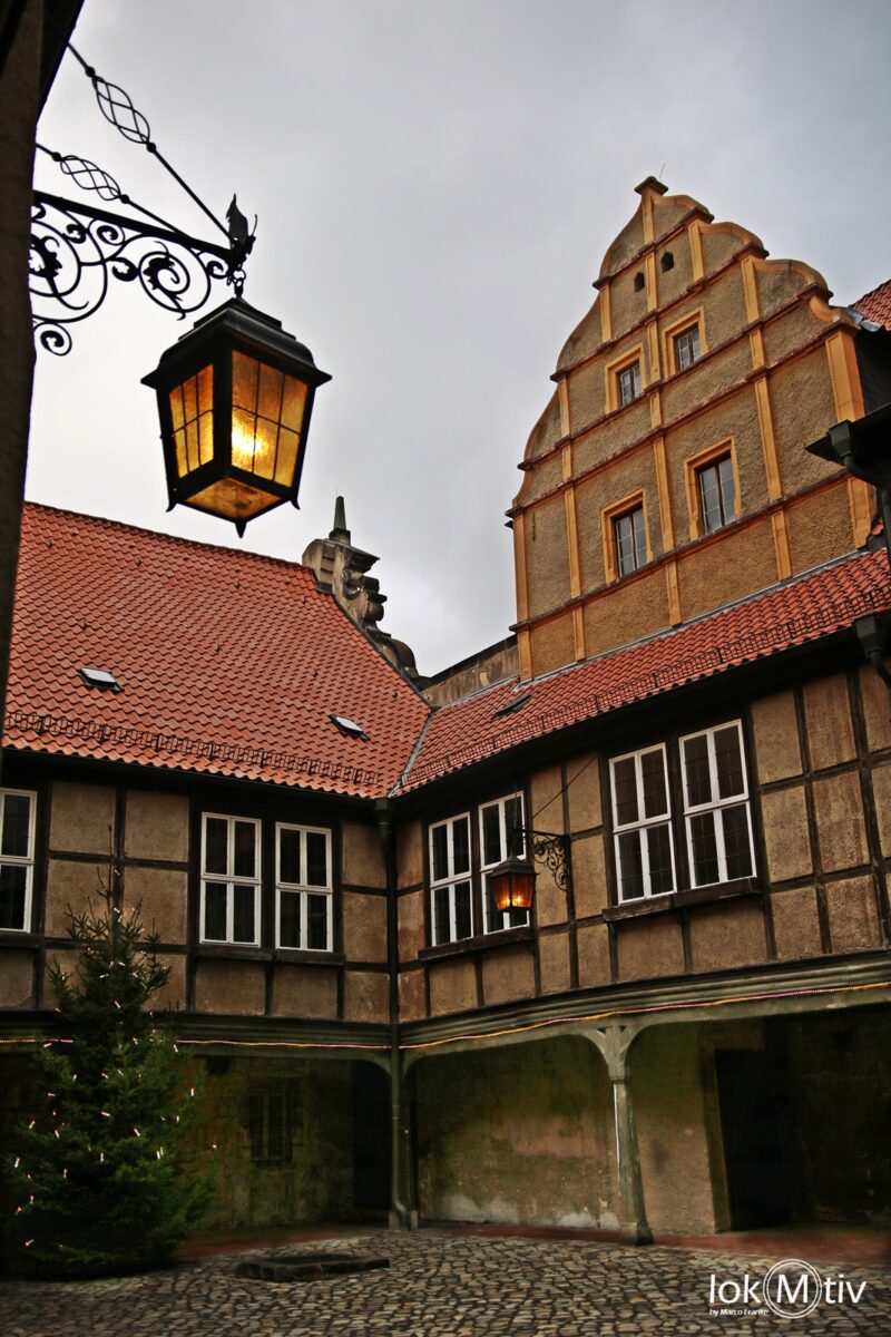 Innenhof des Doms mit Fachwerksbau und einer Wandlaterne.