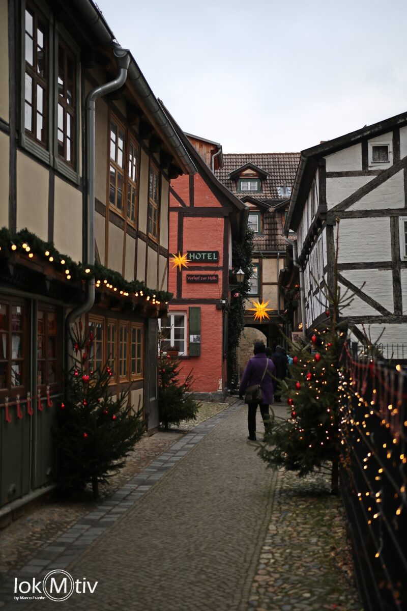 Gasse in Quedlinburg mit geschmückten Weihnachtsbäumen und Fachwerkhäusern.
