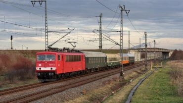 Das Bild zeigt eine E-Lok der Baureihe 155, ex DR 250, auch als Energiecontainer bezeichnet vor dem Museumszug des Eisenbahnmuseums.