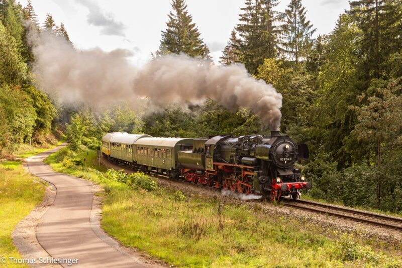 Das Bild zeigt den Museumszug mit Dampflok 52 8154 bespannt in einer Steigung im Wald nach Oberhof.