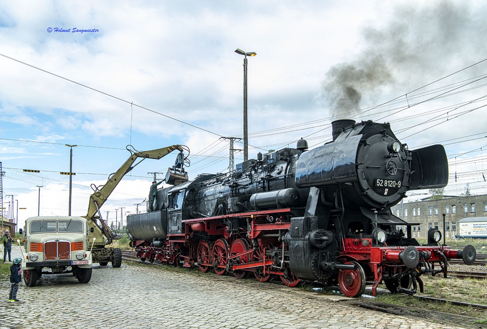 Das Bild zeigt, wie 52 8154 des EMBB bekohlt wird. In Nutzung ein historischer Radbagger, welcher die Steinkohle von einem historischen LKW S4000 aufnimmt und in den Tender der Lok befördert.