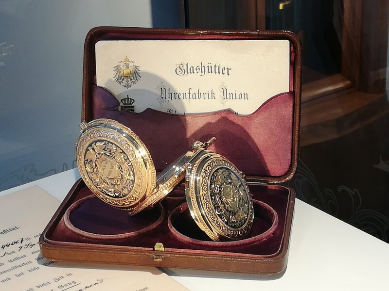 Das Bild zeigt eine goldene kunstvoll verziehrte Herrentaschenuhr im aufgeklappten Zustand.