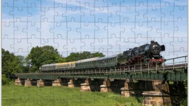 Das Bild zeigt die Puzzle Vorlage Museumszug in Kössern. Die Vorlage zeigt den Zug bei der Überquerung der Auenbrücke.