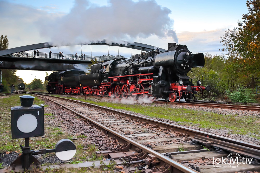 Das Bild zeigt die beiden Dampflokomotiven 52 8195 und 52 8154, welche Tender an Tender gekuppelt sind und gemeinsam unter Dampf Führerstandsmitfahrten machen. Im Hintergrund die Füßgängerbrücke.