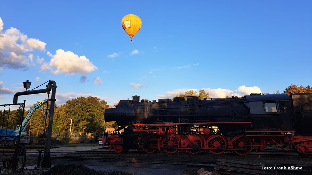 Das Bild zeigt einen gelben Heißluftballon über der Dampflok 52 8098 im BW Plagwitz.