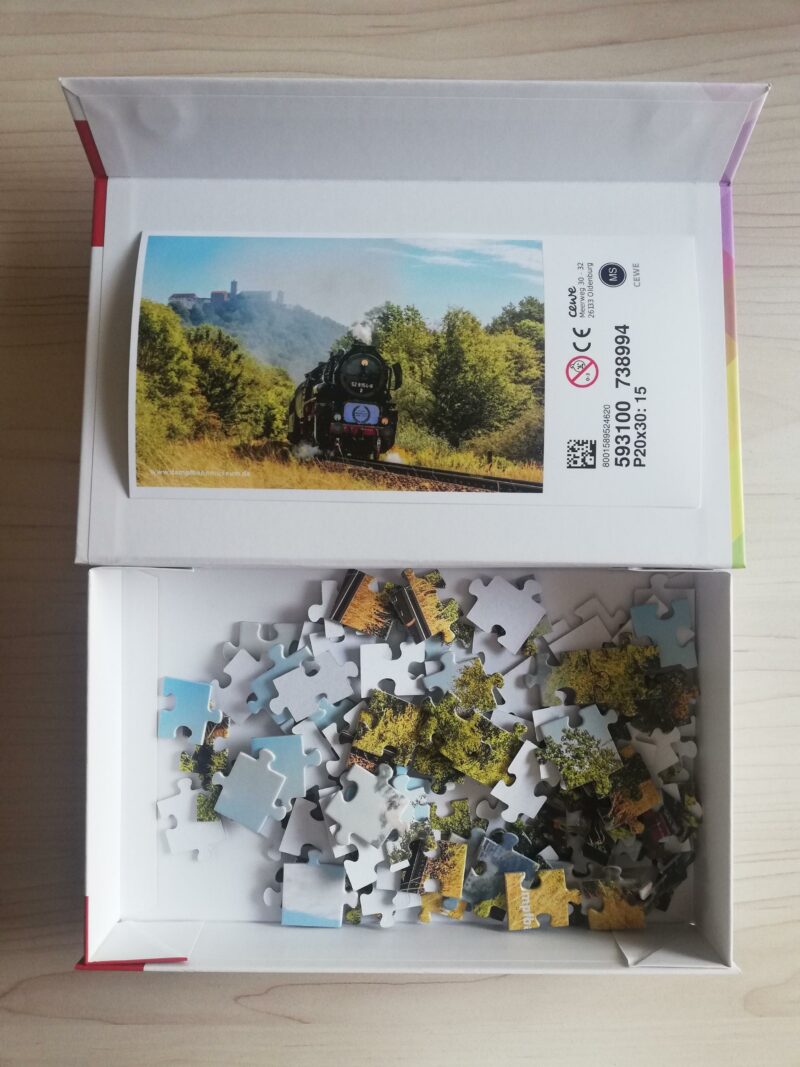Zeigt den Lieferumfang mit Musterfoto und Box.