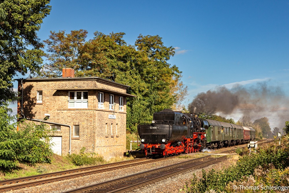 Am Block Zauschwitz, einem Backsteinstellwerk mit nebenliegendem Bahnübergang. 52 8195 ist gerade auf dem Bahnübergang. Der Zug besteht aus DB Umbauwagen, Mitropa und Begleitwagen.