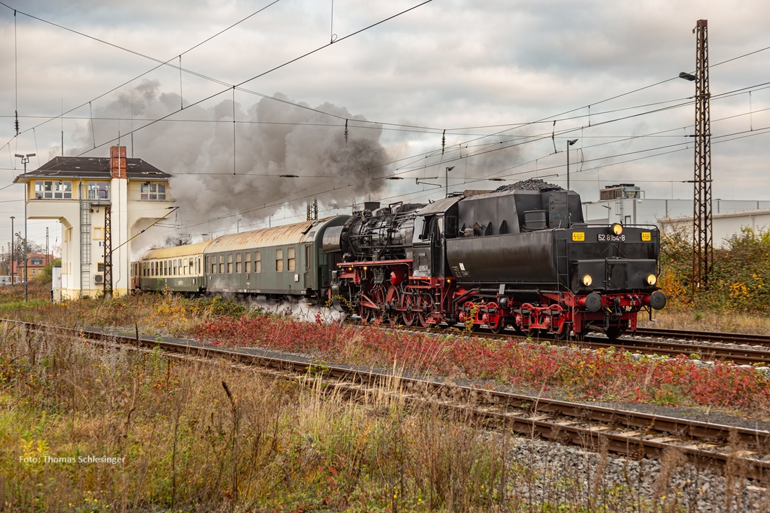 Zu sehen ist Dampflok 52 8154 Tender voran am Zug hängend bei der Ausfahrt Borna. Links neben dem Zug ein Stellwerk.
