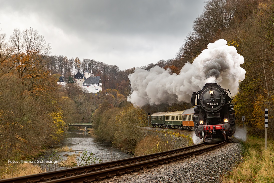 Der Museumszug des Eisenbahnmuseums Leipzig passiert gezogen von der Dampflok 52 8154 Rauenstein. Über dem Fluss Zschopau, den der Zug rechterhand folgt, liegt links erhöht die Burg Rauenstein.