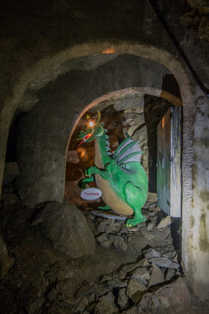 Zu sehen ist das Maskottchen der Drachenhöhle, ein Drache namens Justus. Er verbirgt sich unter gemauerten Gewölben.