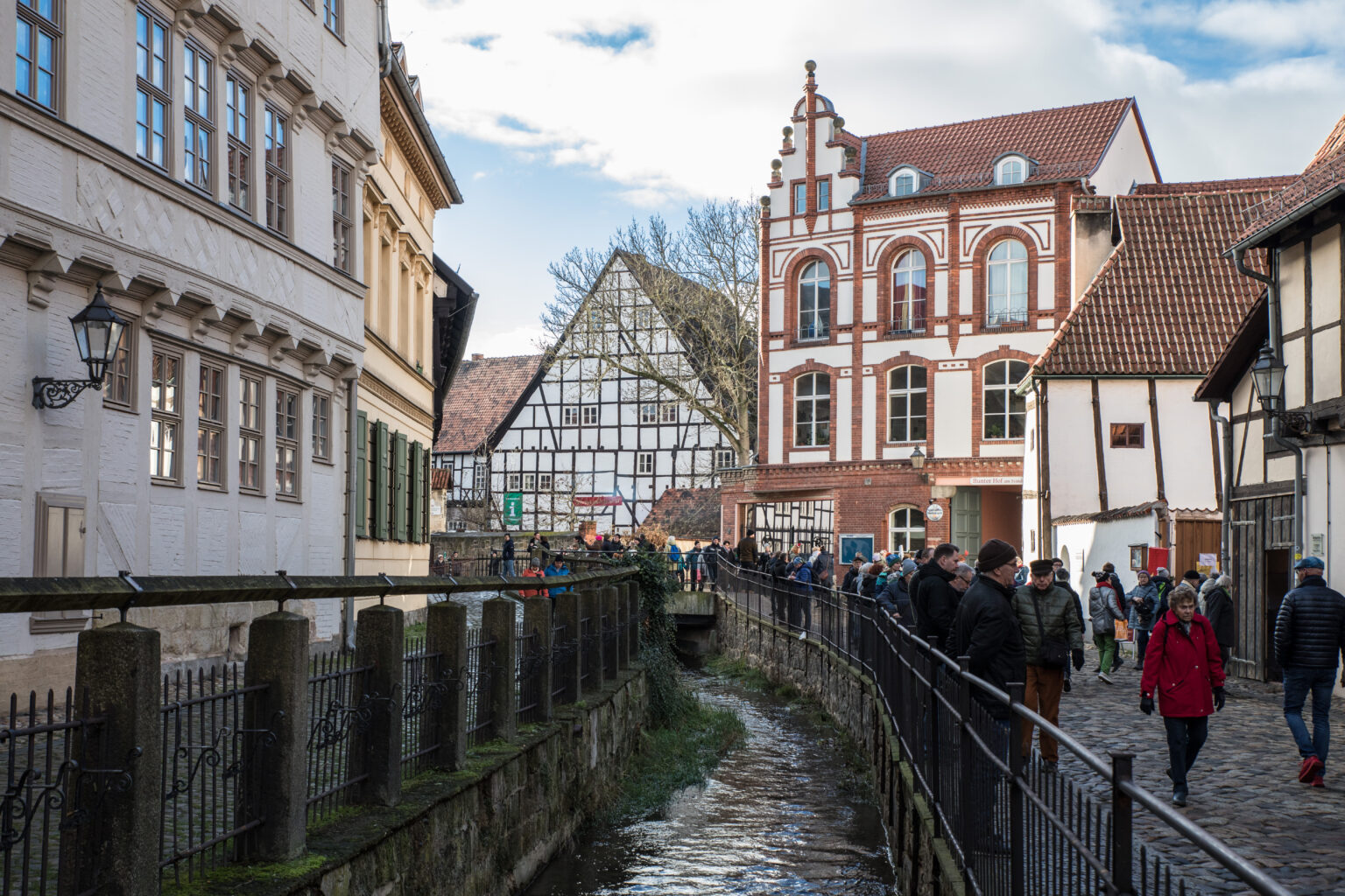 Das Bild zeigt eine Häusergasse mit einer Bach in der Mitte. Beidseitig der Bach sind Wege mit Geländern.