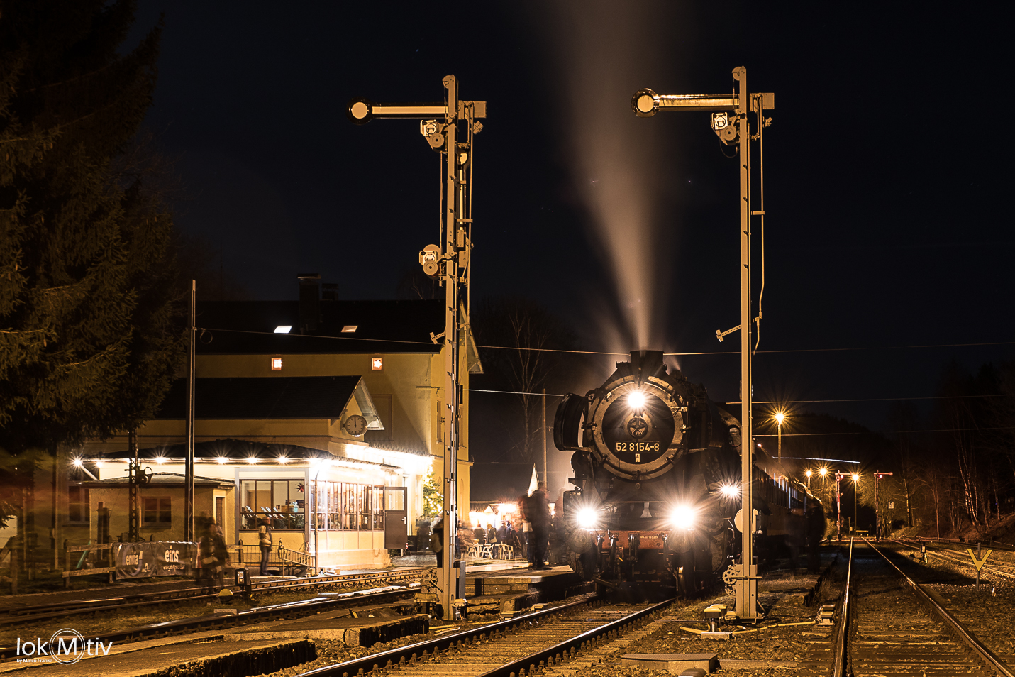 Das Bild zeigt den Museumszug bei Nacht im Bahnhof Schlettau. Vorn zwei Formsignale, links das Bahnhofsgebäude...