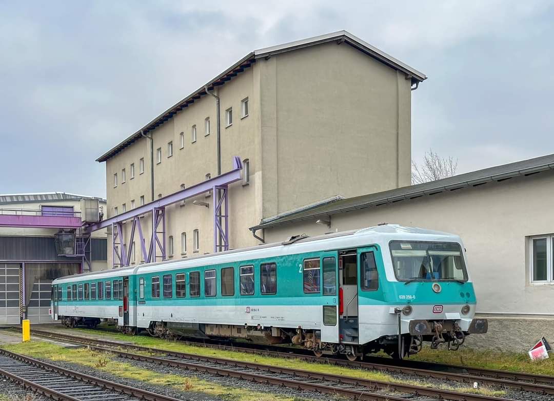 Dieseltriebwagen in Mintfarbgebung der DB vor einem Bahnbetriebswerk.